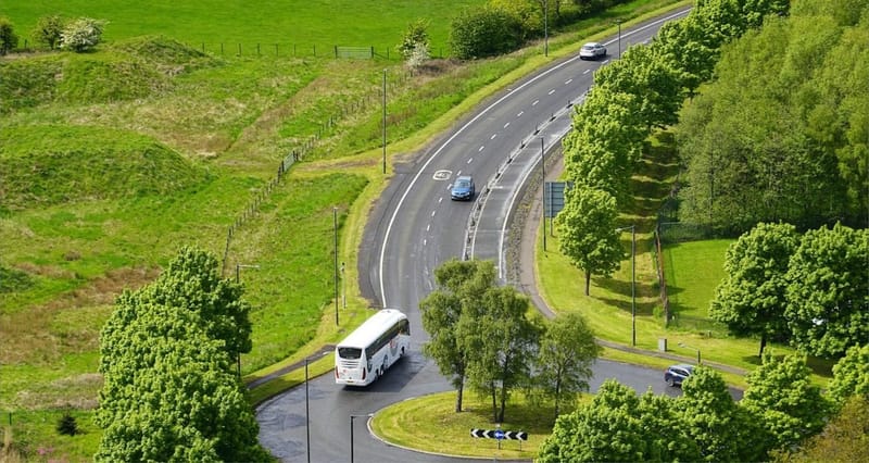 A coach on a winding road through green hills
